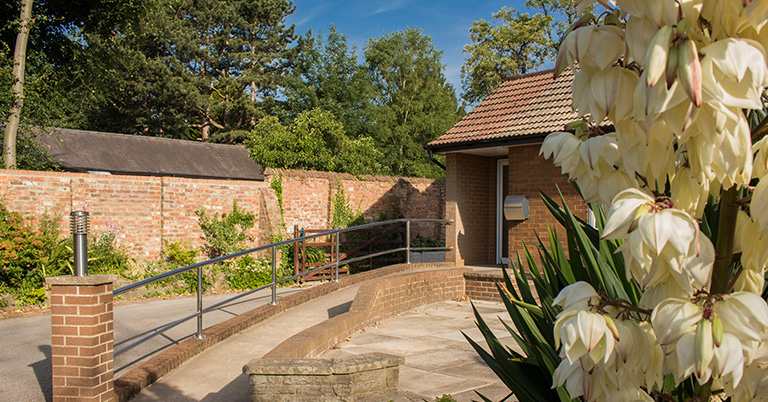 Zoomed-in shot of Acomb Chiropractic Clinic, an accessible ramp leading to the door with flowers in the foreground.