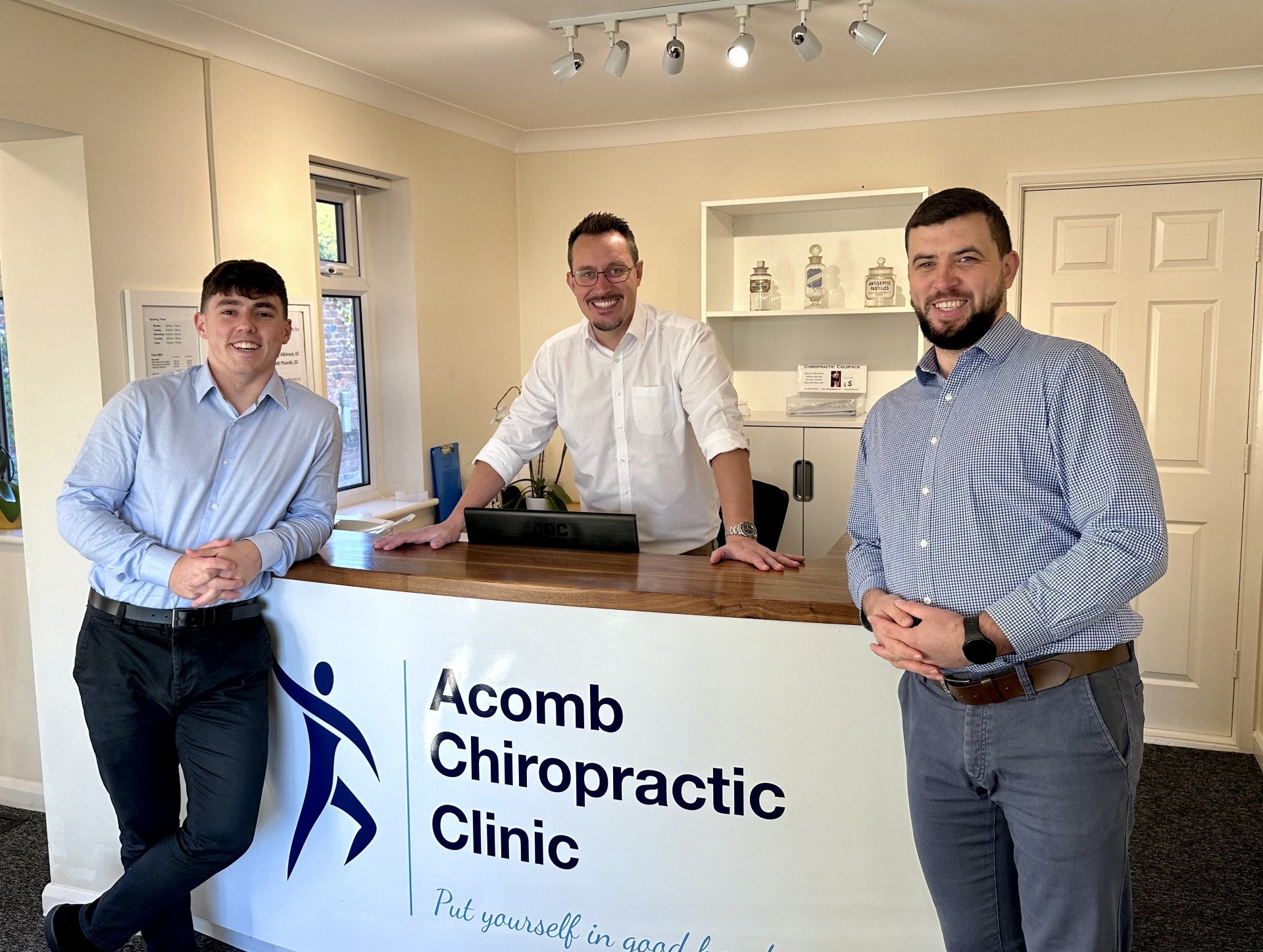 York Chiropractors, Henry, Jonathan and Matt Photograph of chiropractors Jonathan Brack, Mateusz Pisarski and Henry Atkinson at the reception desk of Acomb Chiropractic Clinic
