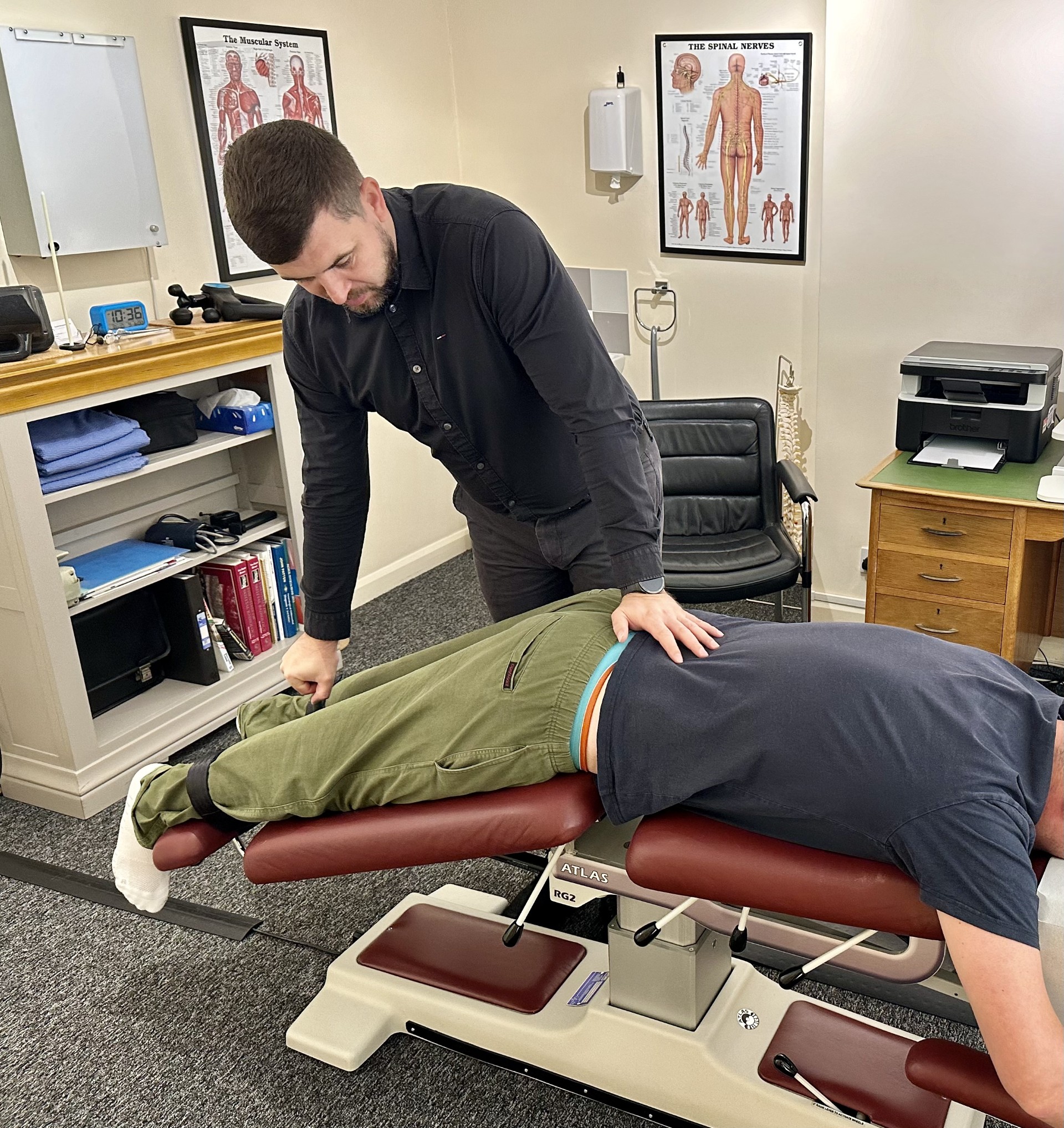flexion-distraction-demonstration-1-1 Photo of chiropractor assessing the lower back of a young male patient.