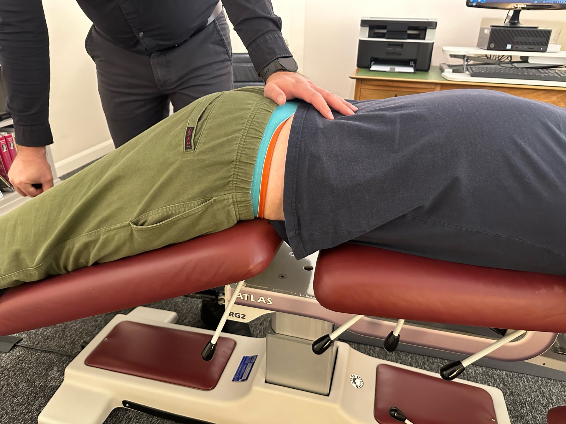 Photo of chiropractor assessing the lower back of a young male patient.