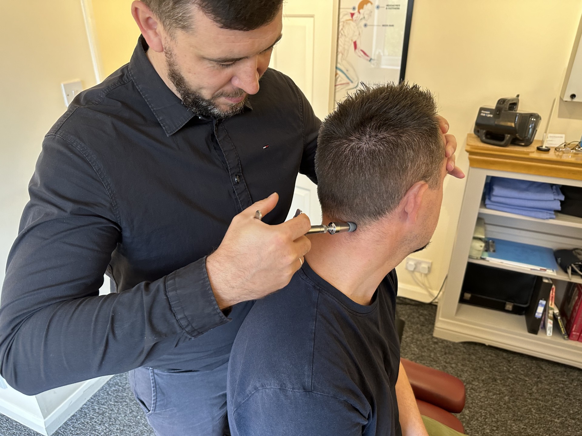 York-Chiropractor-discusses-treatment-techniques-activator Photo of Chiropractor using chiropractic activator on the back of a young man's head.